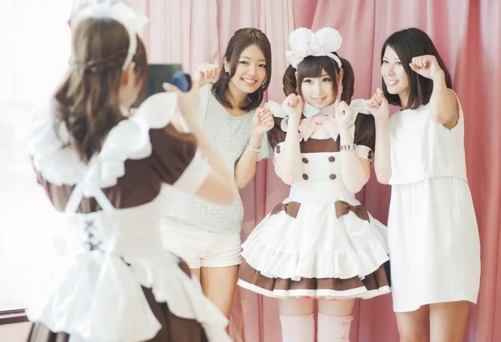 Twee Japanse vrouwen gaan op de foto met een Maid Café serveerster