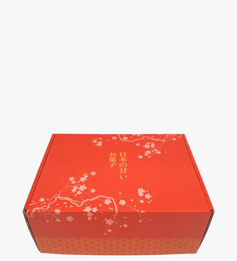 Rode kartonnen geschenkenbox met delicate witte kersenbloesem- en goudbladpatronen, met Japanse tekst langs de zijkant.