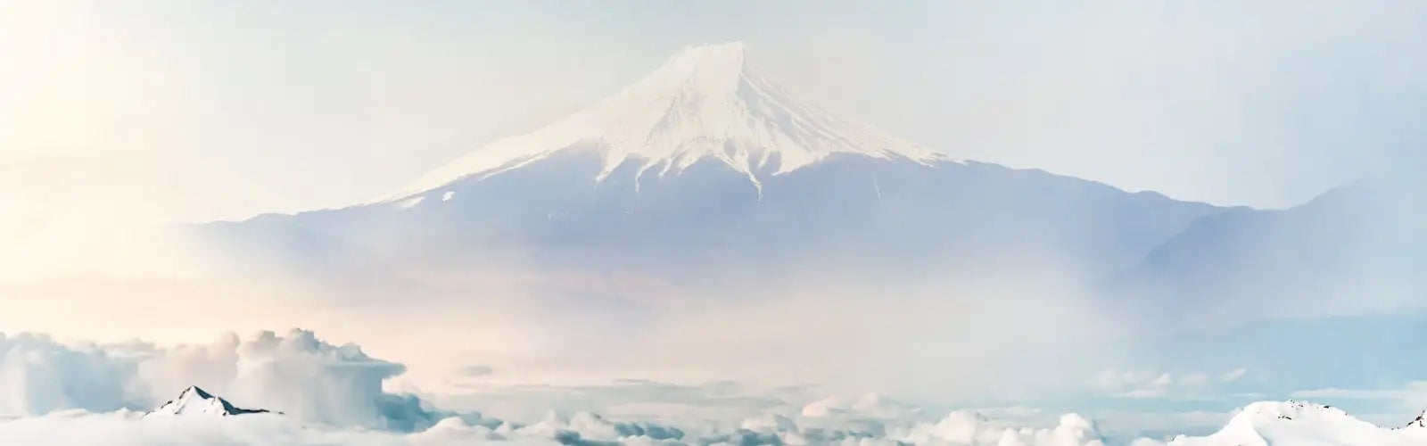 Sneeuwbedekte berg Fuji rijst majestueus op tegen een zachte, nevelige hemel.