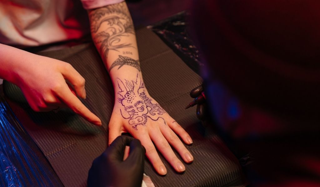 iemand die een tatoeage van een Japanse draak op zijn hand laat zetten
